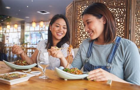 Premium Photo | Restaurant girl friends and talking with food noodles ...