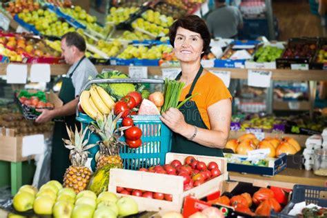 Vendedora De Mulheres Que Demonstra Cesto Legumes E Frutas Foto De