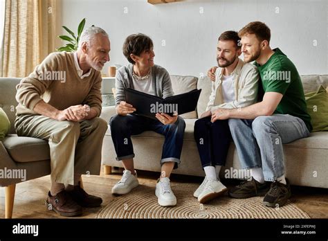 A Gay Couple Sits On A Couch With Parents Looking At A Photo Album Stock Photo Alamy
