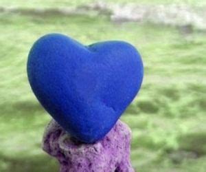 A Blue Heart Sitting On Top Of A Purple Rock