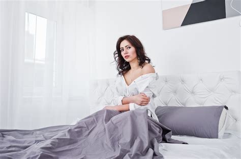 Premium Photo Studio Portrait Of Brunette Girl In White Blouse Lying On Bed