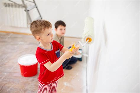 Premium Photo | Children paint a wall with brush and roller in white ...