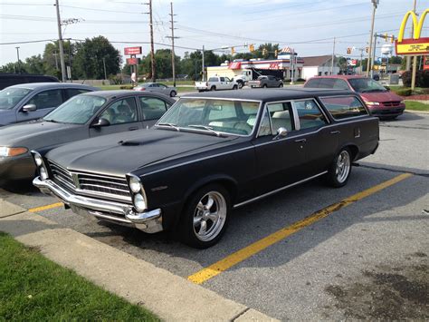 An Old Black Station Wagon Parked In A Parking Lot