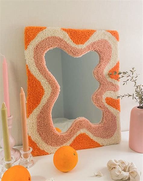 An Orange And White Decorative Mirror Sitting On Top Of A Table Next To