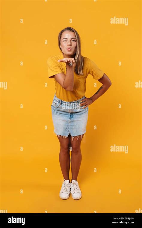 Image d une femme blonde joyeuse qui se fait sauter et souffle baiser d air isolé sur fond jaune