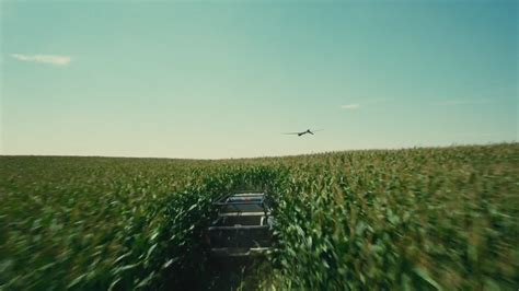 An Airplane Flying Over A Corn Field With A Truck In The Foreground And