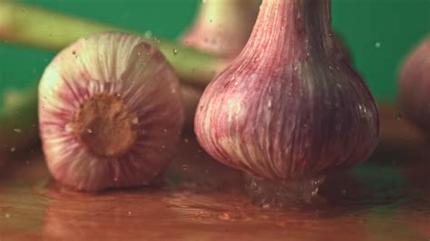 Super Slow Motion Garlic Falls On The Table On A Green Background