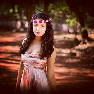 A Woman With Long Hair Wearing A Dress And Flowers In Her Hair Standing