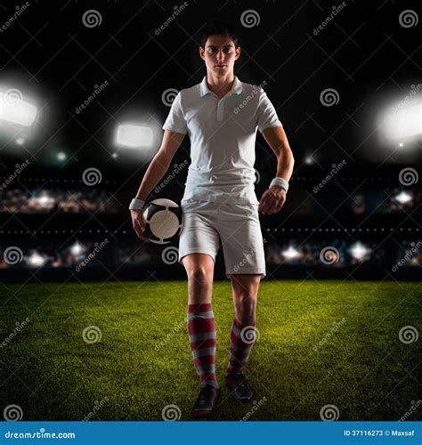 Young Man Football Player Walks On Grass Field With Ball In Hand Stock