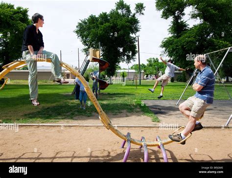 Adults play on children's playground equipment in Salina, Kansas, USA ...