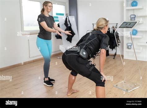 Woman in EMS suit performing exercises with personaö trainer guidance ...