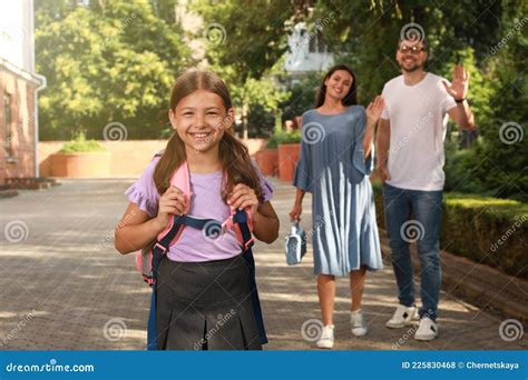 Parents Waving Goodbye To Their Daughter Before School Outdoors Stock