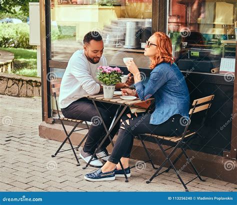 A Couple Dating Drinking Coffee Sitting Near The Coffee Shop Outdoors