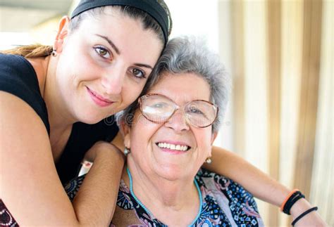 Grandmother Smiling With Her Granddaughter On Terrace Of Her House