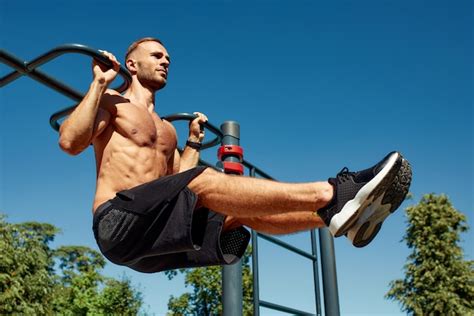 Homem bonito no campo esportivo o esportista o cara realiza exercícios