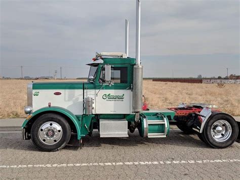 A Green And White Semi Truck Parked On The Side Of The Road In Front Of