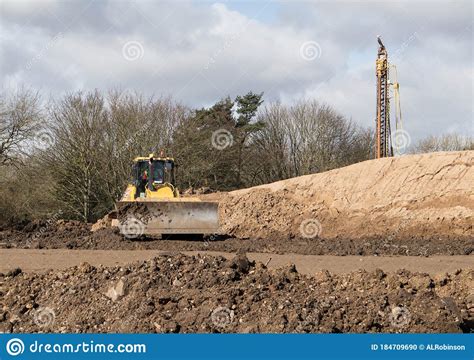 A Bulldozer Moving Sand On A Sandy Beach With The Ocean Water In The