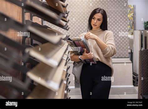 Happy Brunette Female Interior Designer Choosing Flooring Tile Color Texture Samples At Store