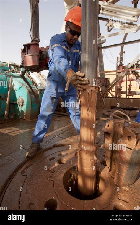 A Drill Rig Roughneck Wipes Drill Mud From Pipe Being Lifted From An