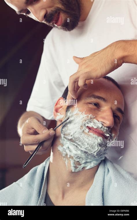 Young man getting an old-fashioned shave at the barber shop. Closeup ...