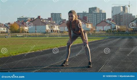 Athletic Blonde Woman Finishing Running And Bending Over To Catch Her Breath Stock Photo