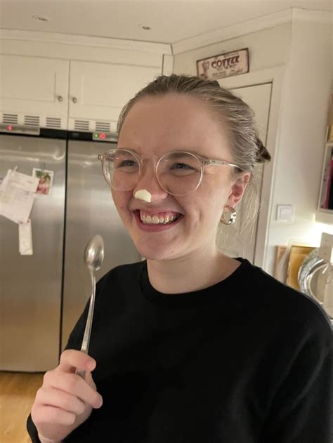 A Woman Wearing Glasses Holding A Spoon In Her Right Hand And Smiling