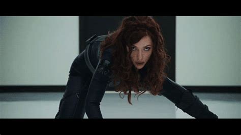 A Woman With Red Hair And Black Gloves Is Looking At The Camera While Standing On One Leg