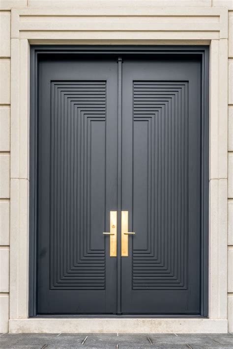 Two Black Double Doors With Gold Handles In Front Of A Building