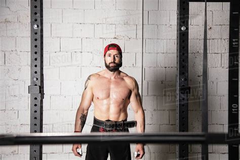 Strong Male Athlete With Naked Torso And In Weightlifting Belt Standing Near Barbell During