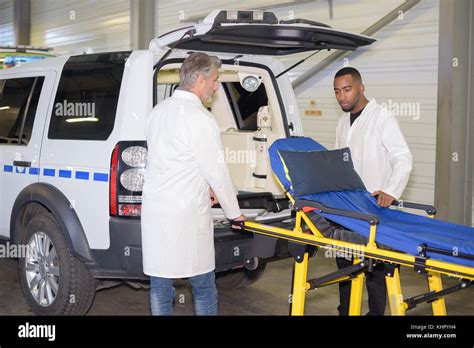 Two Men Loading Empty Stretcher Into Ambulance Car Stock Photo Alamy