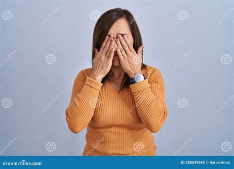 Middle Age Brunette Woman Standing Wearing Orange Sweater Rubbing Eyes For Fatigue And Headache