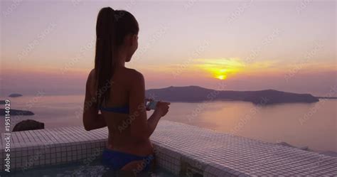 Europe Travel Woman In Bikini In Pool Spa By Taking Photo Using Phone Of Sunset View On Vacation