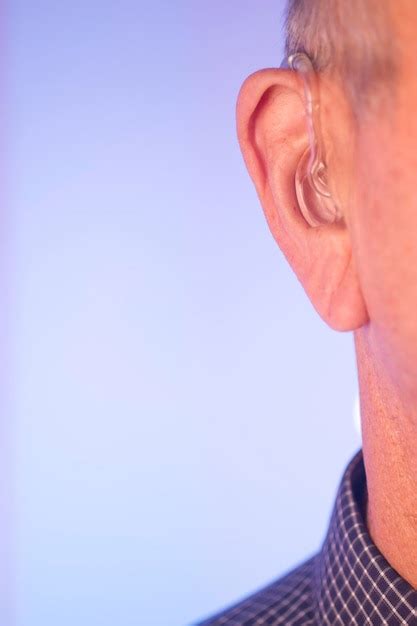 Premium Photo Close Up Of Man Wearing Hearing Aid Against Colored