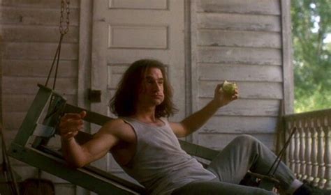 a man sitting on a porch swing holding an apple in one hand and looking ...