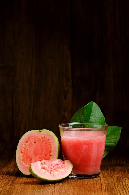 El Jugo De Guayaba Roja Se Sirve Sobre Un Fondo De Madera Con Rodajas