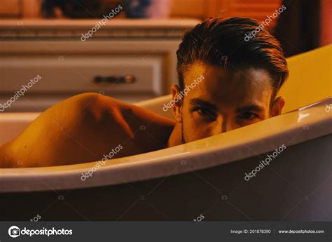 Guy In Bathroom With Toiletries On Background Macho Sitting Naked In Bathtub Pretending To Hide