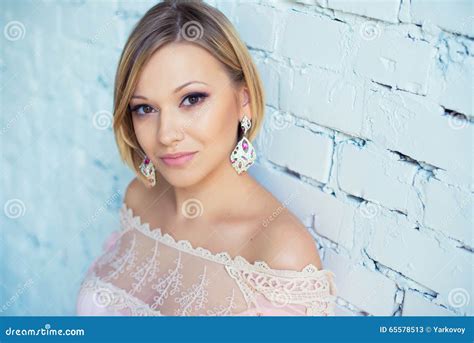 Portrait De Femme Blonde Assez Jeune Avec Les Cheveux Courts Sur Un Fond Du Mur De Briques Blanc