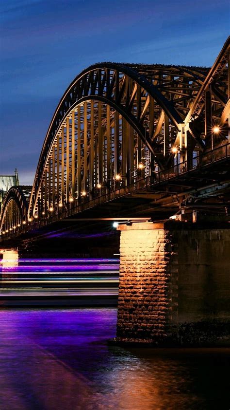 A Bridge That Has Some Lights On It And Is Lit Up In The Night Time