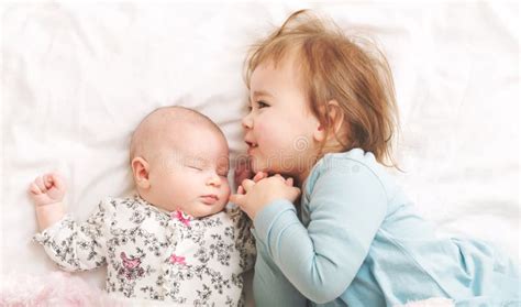 Niña Pequeña Que Juega Con Su Hermana Recién Nacida Foto de archivo