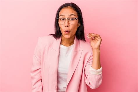Mujer latina joven aislada sobre fondo rosa riendo de algo tapándose