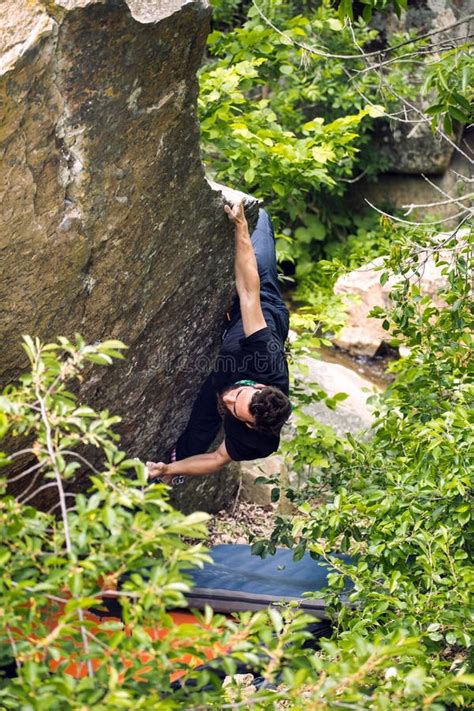 Bouldering On Natural Terrain A Strong Man Climbs A Boulder Stock