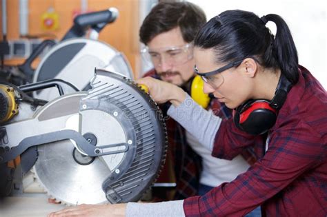 Carpenter And Female Apprentice Working Together In Workshop Stock