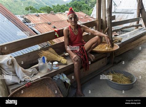 Senior Ifugao Man In Traditional Costume Sitting On A Wooden Bench On