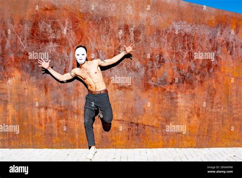 Shirtless Man Wearing White Mask Dancing With Arms Outstretched While