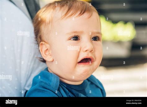 Close Up Portrait Of Upset Crying Baby Sitting In A Buggy Stock Photo