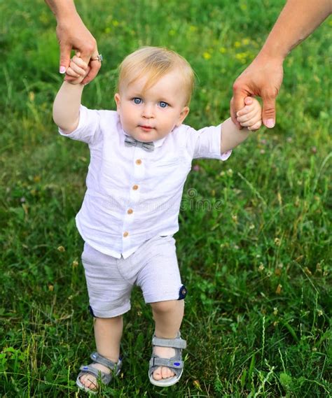 Father And Mother Parents Holding Hands Baby Walking Together On Grass