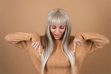 Fille Blonde Avec Une Frange Et Un Maquillage De Jour Marron Dans Un Pull Sur Fond Beige Sourit