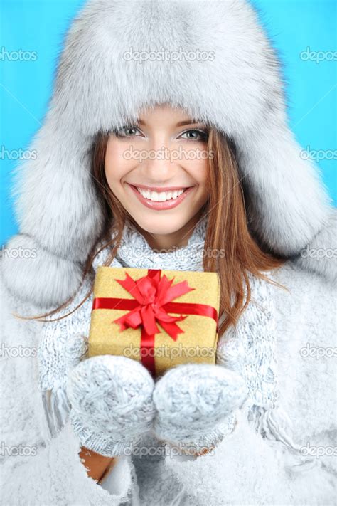 Beautiful smiling girl in hat with gift on blue background Stock Photo by ©belchonock 36000169