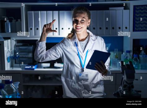 Wunderschöne blonde Frau spät in der Nacht im Wissenschaftlerlabor arbeitet lächelt und