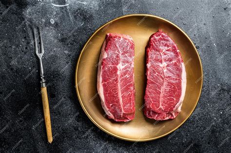 Premium Photo Raw Shoulder Top Blade Beef Meat Steaks On A Plate Black Background Top View